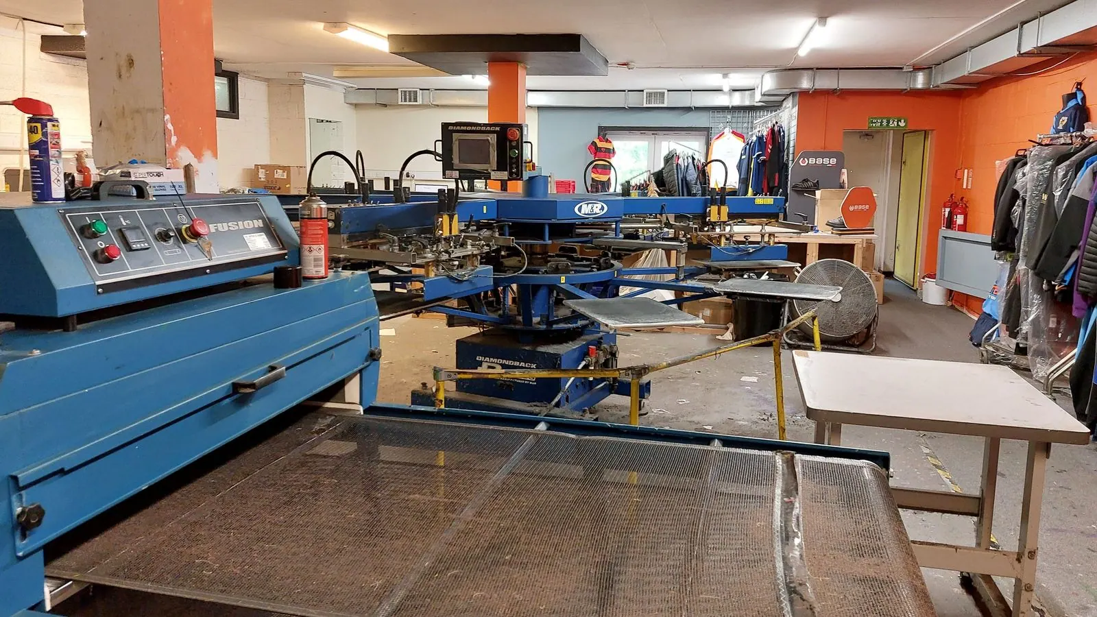 A screenprint carousel and press on a workshop floor, print tables alongside.